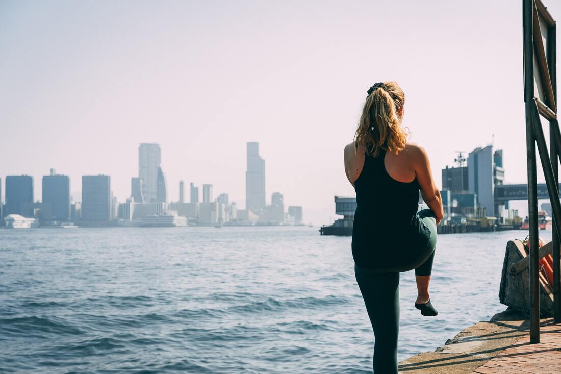 Woman exercising near water with city skyline in background
